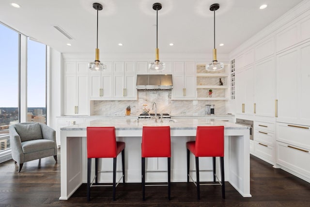 kitchen featuring white cabinetry, an island with sink, pendant lighting, and crown molding