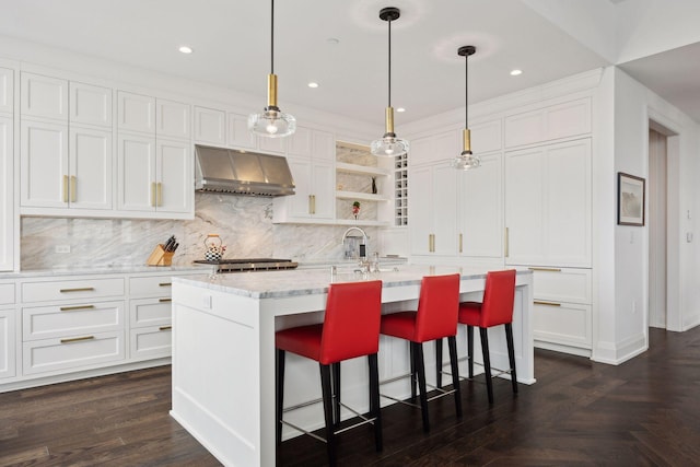 kitchen featuring white cabinetry, hanging light fixtures, a kitchen island with sink, and exhaust hood