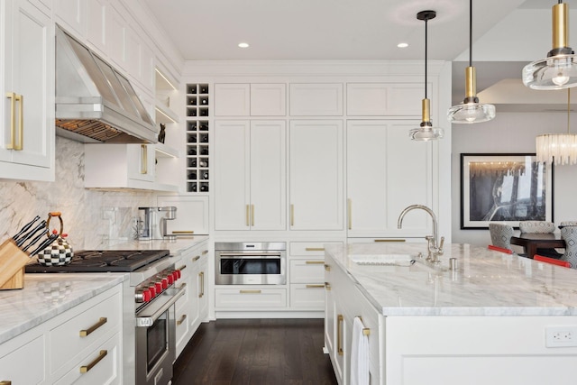 kitchen with appliances with stainless steel finishes, decorative light fixtures, sink, light stone counters, and custom range hood