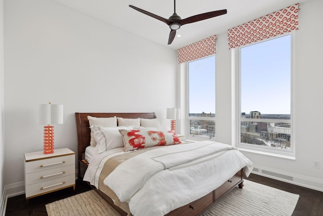 bedroom with ceiling fan, dark hardwood / wood-style flooring, and multiple windows