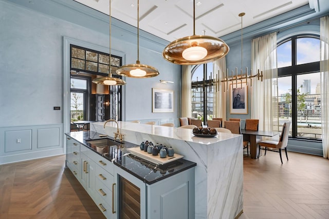 kitchen with dark parquet flooring, coffered ceiling, sink, hanging light fixtures, and white cabinets