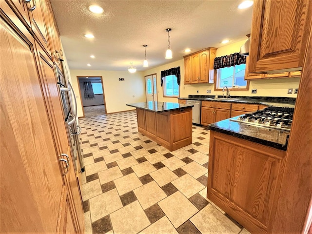 kitchen featuring appliances with stainless steel finishes, a textured ceiling, sink, pendant lighting, and a kitchen island