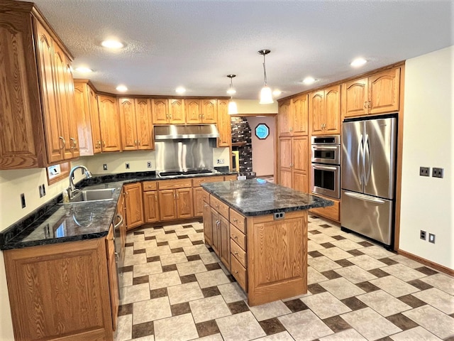 kitchen featuring sink, stainless steel appliances, dark stone countertops, pendant lighting, and a kitchen island