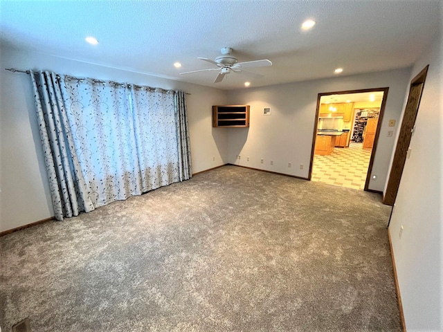 carpeted spare room featuring ceiling fan and a textured ceiling