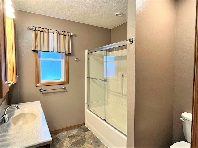 full bathroom with a textured ceiling, vanity, toilet, and bath / shower combo with glass door