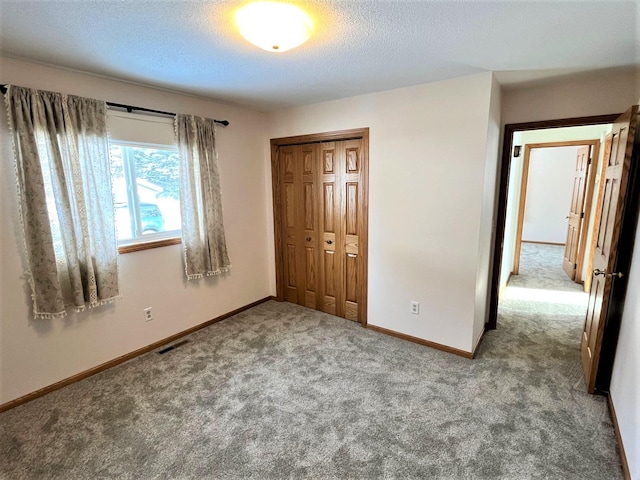 unfurnished bedroom with light colored carpet, a textured ceiling, and a closet