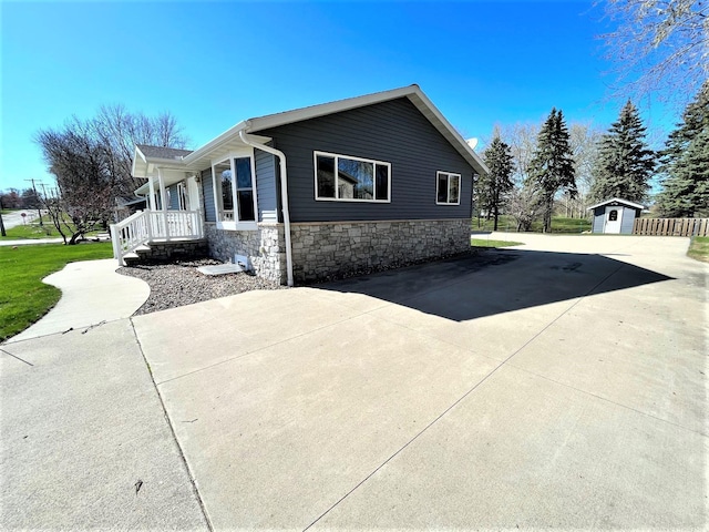 view of side of home with an outdoor structure, stone siding, and a storage unit