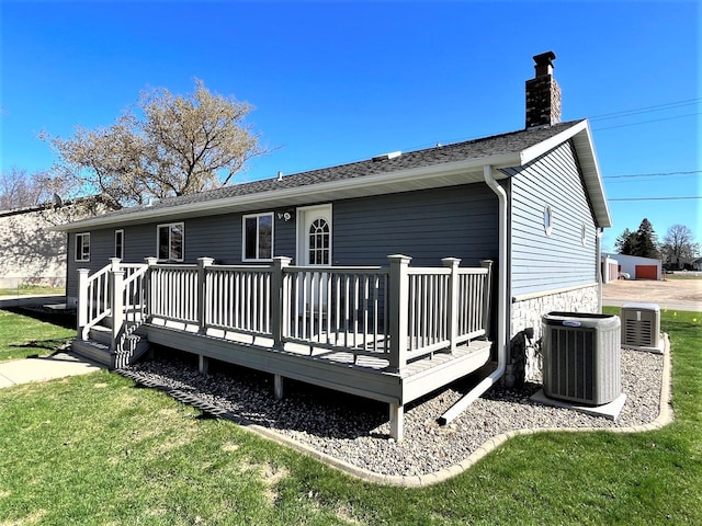 rear view of property with a yard, a deck, cooling unit, and a chimney