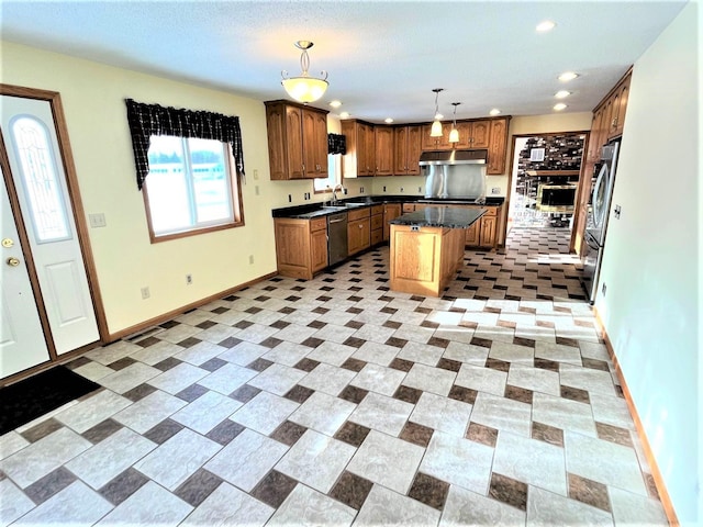 kitchen featuring a kitchen island, dark countertops, a sink, under cabinet range hood, and stainless steel appliances
