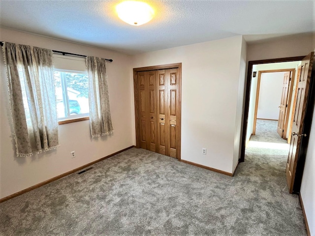 unfurnished bedroom featuring visible vents, carpet floors, a closet, baseboards, and a textured ceiling
