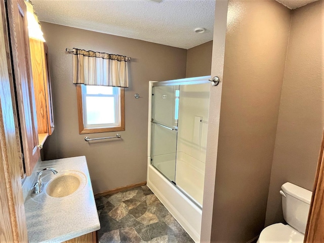 bathroom with toilet, a textured ceiling, baseboards, stone finish flooring, and combined bath / shower with glass door