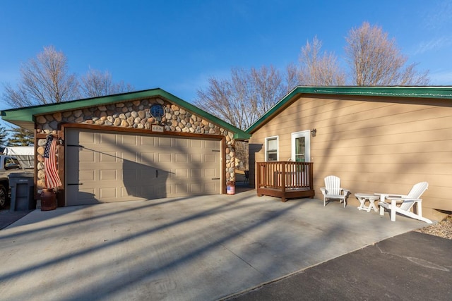 exterior space with stone siding, a detached garage, and an outdoor structure