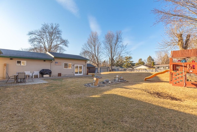 view of yard with an outbuilding, a patio area, a playground, and fence