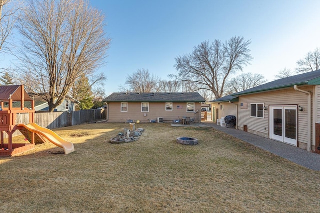 rear view of property featuring a patio, a playground, a fenced backyard, a fire pit, and a yard