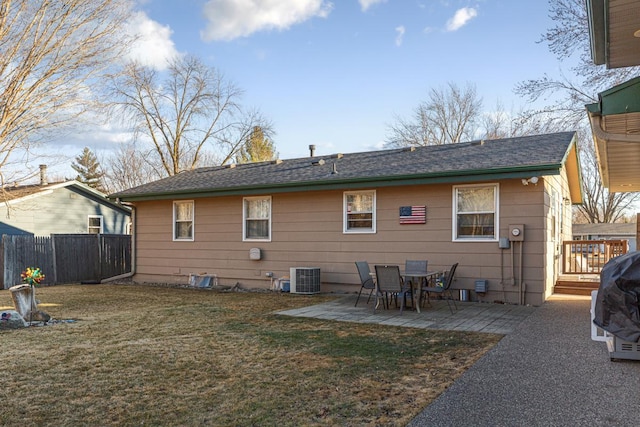 rear view of property featuring fence, a lawn, central AC unit, and a patio