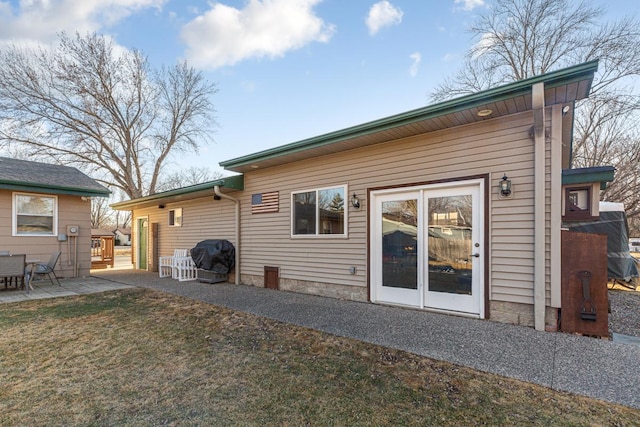 back of property featuring a patio area and a lawn