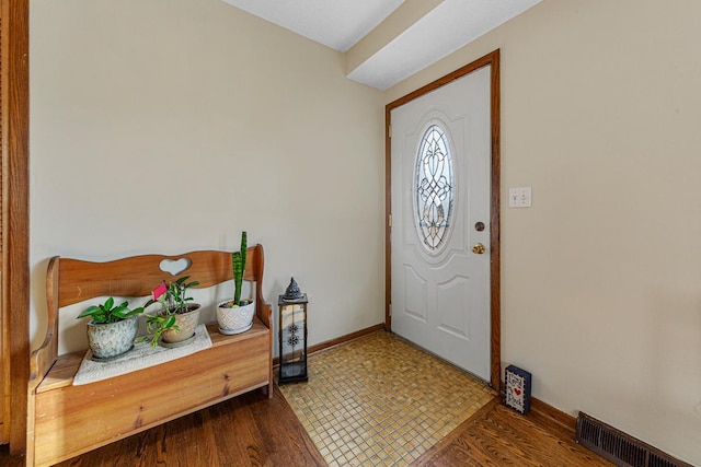 foyer entrance featuring baseboards, visible vents, and wood finished floors