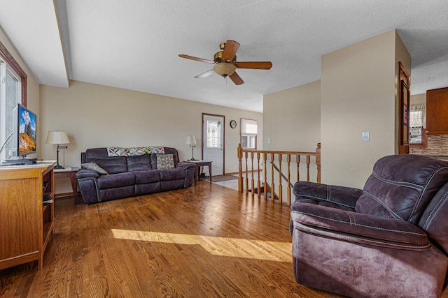 living area with ceiling fan, a textured ceiling, and wood finished floors