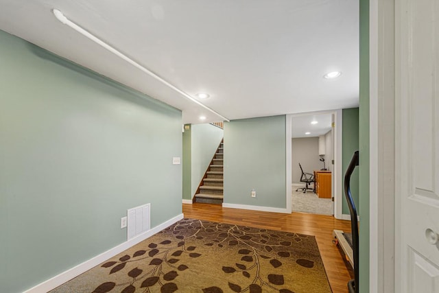 finished below grade area with baseboards, visible vents, stairway, wood finished floors, and recessed lighting