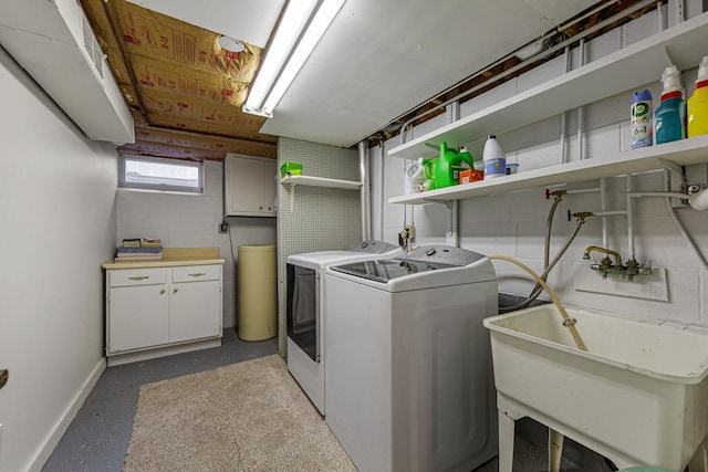 clothes washing area featuring cabinet space, a sink, baseboards, and separate washer and dryer