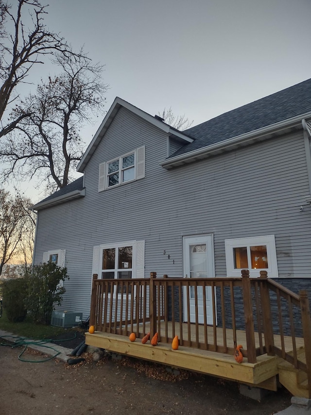 back of property with central AC unit and a deck