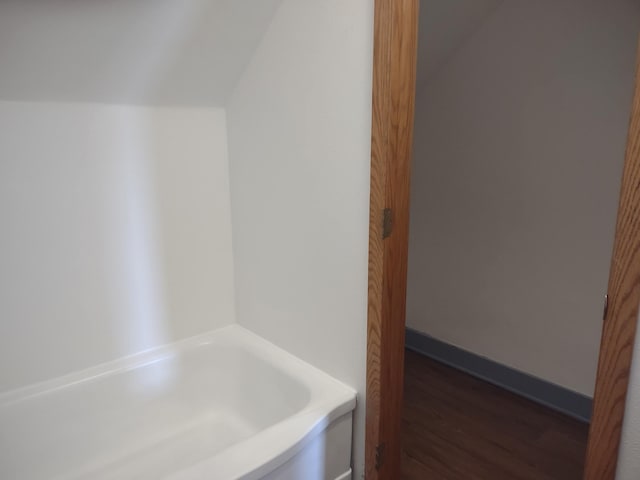 bathroom featuring lofted ceiling, a tub to relax in, and hardwood / wood-style floors