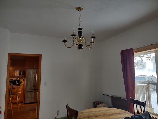 bedroom with hardwood / wood-style flooring, stainless steel fridge, and a notable chandelier