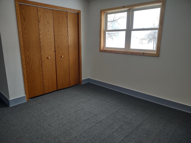 unfurnished bedroom with a closet and dark carpet