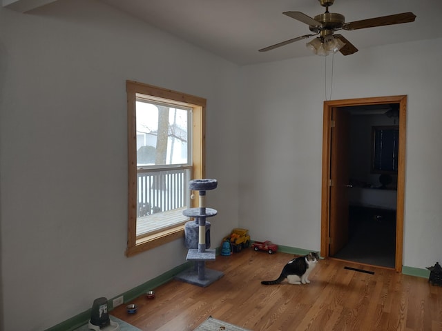 exercise area featuring baseboards, wood finished floors, and a ceiling fan