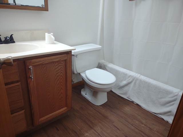 full bath with toilet, a shower with shower curtain, wood finished floors, and vanity