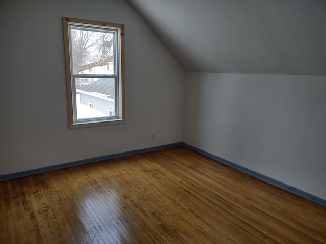 additional living space featuring baseboards, vaulted ceiling, and wood-type flooring