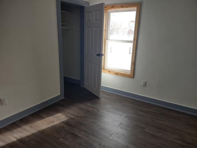 unfurnished bedroom with dark wood-style flooring, a closet, and baseboards