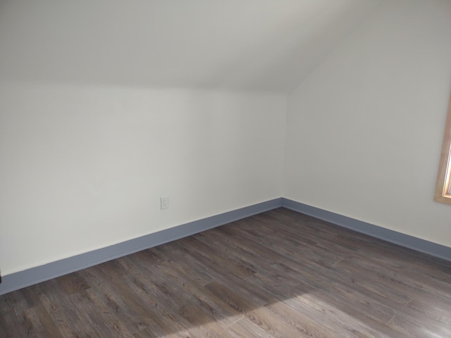 bonus room featuring dark wood-type flooring, lofted ceiling, and baseboards