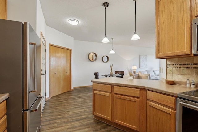 kitchen featuring hanging light fixtures, stainless steel appliances, dark hardwood / wood-style floors, a textured ceiling, and decorative backsplash