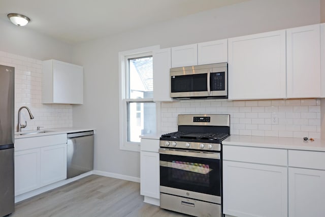 kitchen featuring white cabinets, appliances with stainless steel finishes, decorative backsplash, and sink