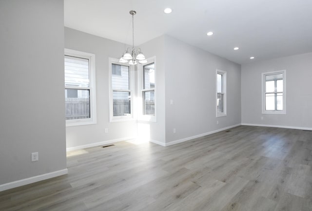 empty room featuring light hardwood / wood-style flooring and a chandelier