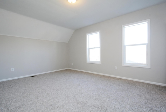 additional living space with carpet flooring and vaulted ceiling