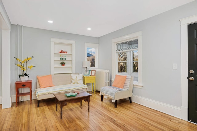 living area featuring radiator, light wood-type flooring, and built in features