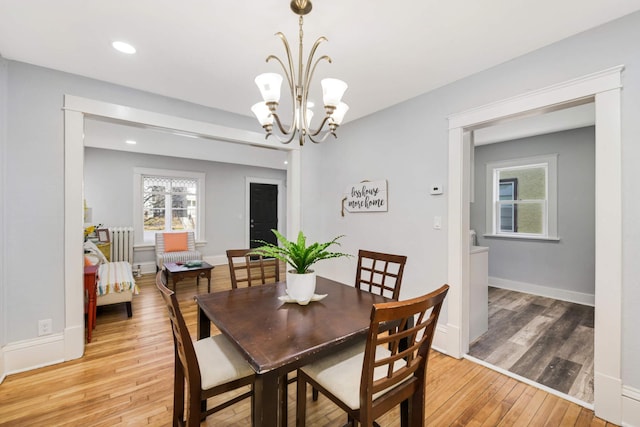 dining area with light hardwood / wood-style floors and a chandelier