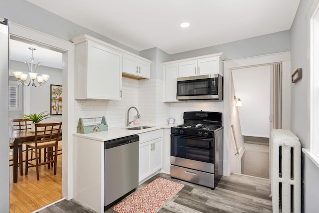 kitchen with white cabinets, sink, stainless steel appliances, and light hardwood / wood-style flooring