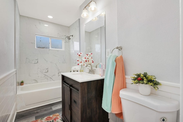 full bathroom featuring hardwood / wood-style flooring, toilet, vanity, and tiled shower / bath combo