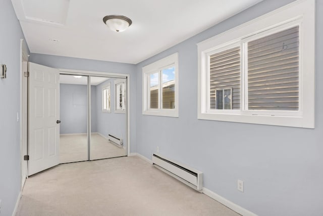 unfurnished bedroom featuring a baseboard heating unit, a closet, and light carpet