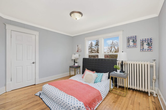 bedroom with crown molding, radiator heating unit, and hardwood / wood-style floors