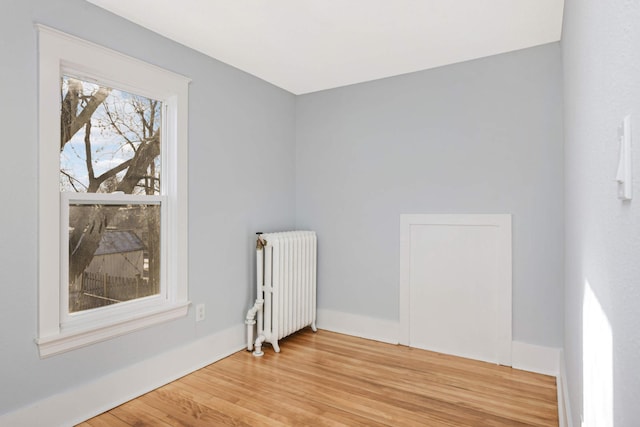 empty room with hardwood / wood-style flooring and radiator heating unit