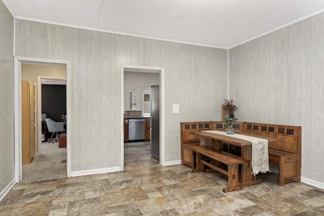 dining space with wood walls and crown molding