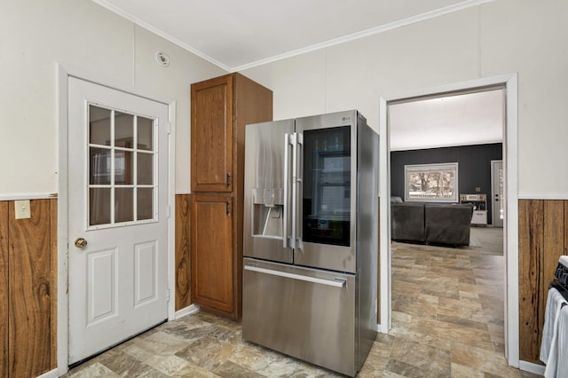 kitchen featuring wood walls, crown molding, and stainless steel fridge