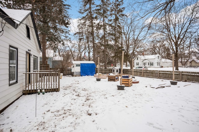 yard layered in snow with a deck and a storage unit