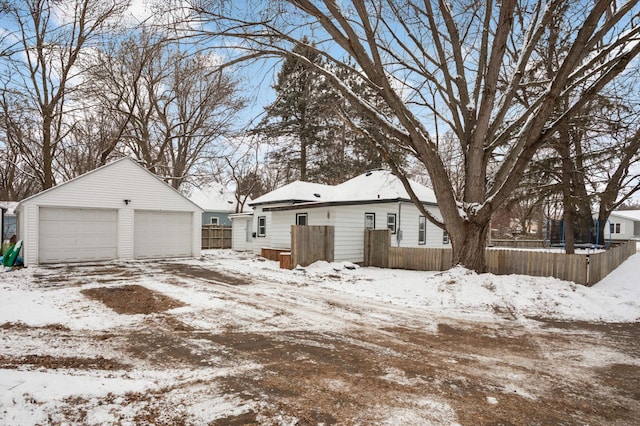 snow covered property featuring a garage and an outdoor structure