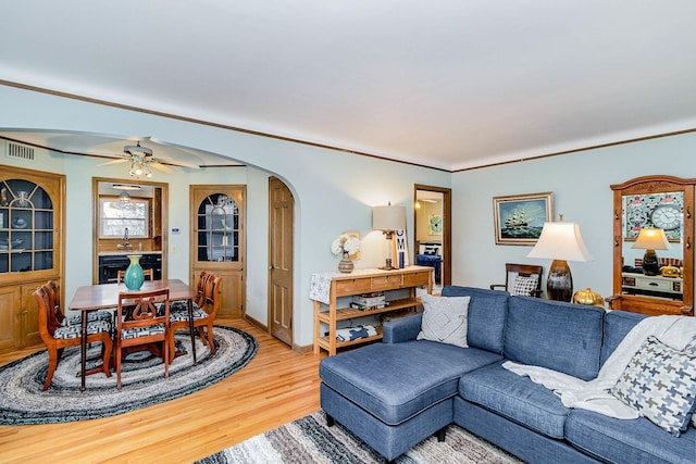 living room with ceiling fan, sink, crown molding, and light wood-type flooring