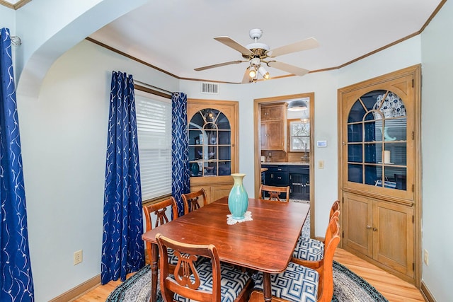 dining room featuring light hardwood / wood-style floors, ornamental molding, and ceiling fan